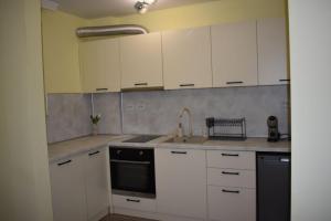a kitchen with white cabinets and a sink at Апартамент за гости Лале in Lovech