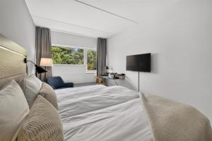 a bedroom with a white bed and a television at Gentofte Hotel in Gentofte