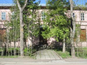 a brick building with trees in front of it at Kogudusemaja külalistoad in Narva-Jõesuu