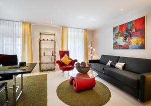 a living room with a black couch and a red chair at GAIA Hotel Basel - the sustainable 4 star hotel in Basel