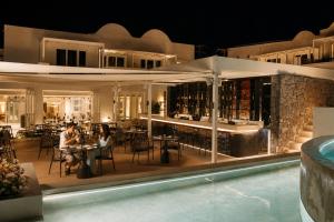 two people sitting at tables in a restaurant next to a pool at Santorini Heart Hotel & Spa in Fira