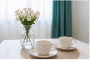a table with two cups and a vase with flowers at Saltanat hotel in Alghabas +4 photos