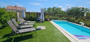 a backyard with a swimming pool with chairs and umbrellas at Luxury Flat with Heated Pool & Jacuzzi in Rijeka