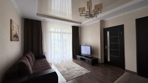 a living room with a couch and a television and a door at Затишні сучасні апартаменти в елітному ЖК Версаль in Truskavets