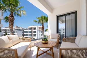 a balcony with white furniture and palm trees at Avenue by Deserve in Paphos