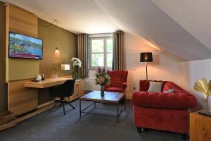 a living room with a red couch and a desk at Landhotel Schnuck in Schneverdingen