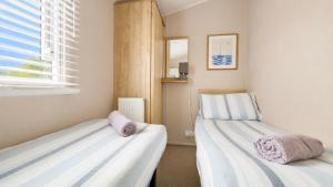 two beds in a small room with a window at Tide & Anchor - Newperran 102 in Cubert +20 photos