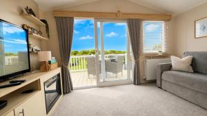 a living room with a television and a balcony at Tide & Anchor - Newperran 102 in Cubert