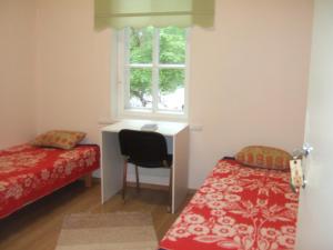 a bedroom with a desk and a bed and a window at Kogudusemaja külalistoad in Narva-Jõesuu
