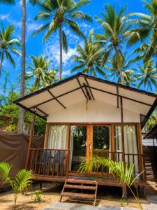 a small house with palm trees in the background at Seashell Cottages Palolem in Canacona