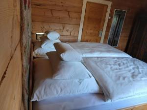 two beds in a room with white sheets and pillows at Bauernhaus in Dzianisz
