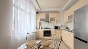 a kitchen with a table and two chairs and a window at Затишні сучасні апартаменти в елітному ЖК Версаль in Truskavets