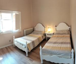 two beds sitting in a bedroom with a window at Cal NEN PAU in Sant Boi de Lluçanès