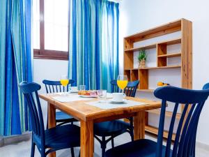 a dining room with a wooden table and blue chairs at Cute Las Flores 1i with pool in Costa de Adeje