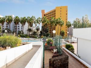 a balcony with a pool and palm trees and buildings at Cute Las Flores 1i with pool in Costa de Adeje
