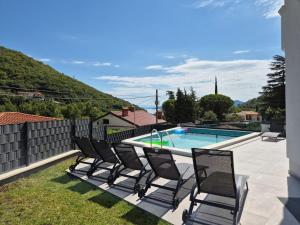 a group of chairs sitting next to a swimming pool at Villa Aylen in Mošćenička Draga