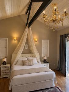 a bedroom with a large bed with a chandelier at Pousada Casa Florinda in Teresópolis