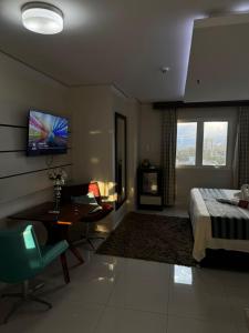 a bedroom with a bed and a desk and a television at Hotel Maestro Premium Cascavel in Cascavel