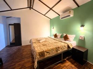 a bedroom with a bed with a green wall at Seashell Cottages Palolem in Canacona