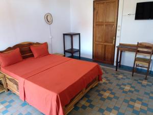 a bedroom with a bed and a table and a television at Hôtel chez Dan in Antsiranana