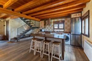 a kitchen with a bar with stools and a staircase at Paraje Navazos in Gavilanes