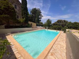 a swimming pool with blue water in a yard at Manoir Jorama - ancien musée de Joséphine Baker in Castelnaud La Chapelle