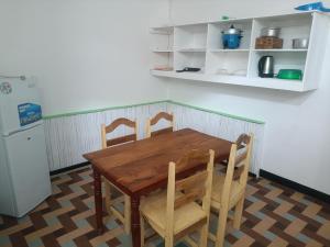 a kitchen with a wooden table and chairs and a refrigerator at Hôtel chez Dan in Antsiranana