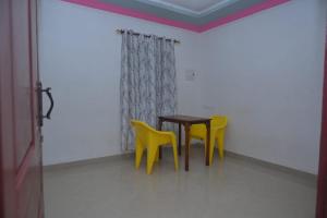 a table and two yellow chairs in a room at Rooms Varkala Homestay in Varkala +49 photos