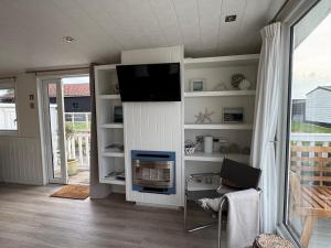 a living room with a fireplace and a tv at Camping Zeezicht - Chalet 16 in Westerland