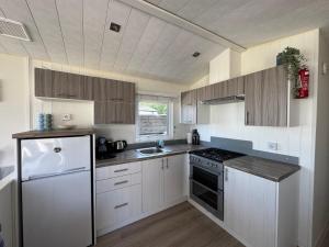 a kitchen with white cabinets and a white refrigerator at Camping Zeezicht - Chalet 16 in Westerland