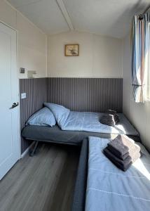a small bedroom with a bed and a window at Camping Zeezicht - Chalet 16 in Westerland