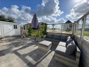 a patio with a couch and an umbrella at Camping Zeezicht - Chalet 16 in Westerland