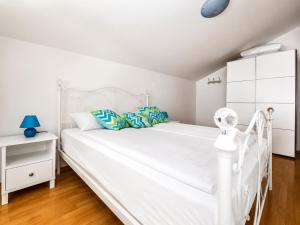 a white bedroom with a white bed and a white cabinet at Mare & Mons Seafront Apartments in Malinska