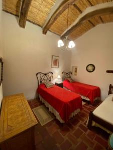 two beds in a room with red sheets at Hosteria El Capricho in Seclantás