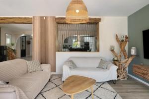 a living room with a couch and a table at Villa Lailléa avec piscine jacuzzi in Laillé