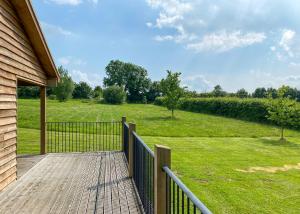 a wooden porch with a fence and a field of grass at Oak Farm Lodges in Roydon