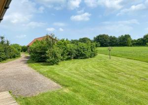 a grassy field with a house and some bushes at Oak Farm Lodges in Roydon
