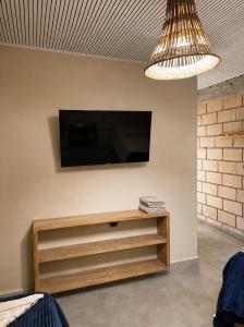 a flat screen tv on a wall with a wooden entertainment center at Hotel Nazareno Coveñas in San Antero