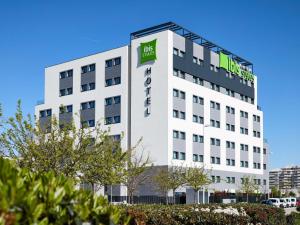 an office building with a green sign on it at Ibis Styles Madrid Airport Valdebebas in Madrid