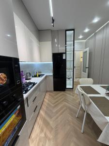 a kitchen with white cabinets and a black refrigerator at Жк Prime Park 2 in Shymkent