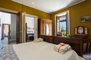 a bedroom with yellow walls and a bed with two pillows at Casa Edera - Villa Storica in Viagrande
