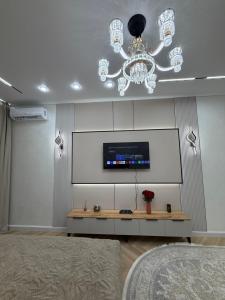 a room with a chandelier and a tv on a wall at Жк Prime Park 2 in Shymkent