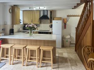 a kitchen with a counter with stools and a refrigerator at Small Barn - Uk52140 in Liskeard