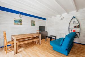 a living room with a wooden table and a blue couch at Gites de l'hivet in Merdrignac