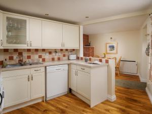 a kitchen with white cabinets and wooden floors at Lark - Ukc6105 in Wootton Fitzpaine