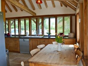 a kitchen with a wooden table with a vase of flowers on it at Romden Barn in Smarden