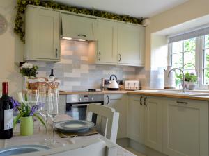 a kitchen with white cabinets and a table with a table sidx sidx sidx at Keldholme Cottages 2 - Uk11488 in Kirkbymoorside