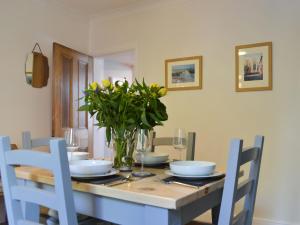 a dining room table with a vase of flowers on it at Dragonfly Cottage in Beverley