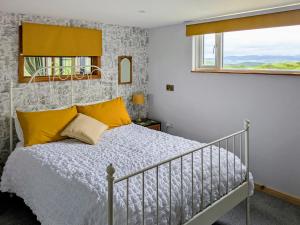 a bedroom with a bed with yellow pillows at Cowlas in Aberhosan +10 photos