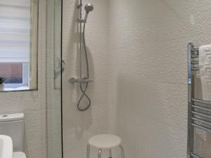 a shower with a glass door with a stool in a bathroom at Wharfdale Lodge in Thornton